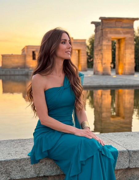 Vestido largo en azul océano con escote asimétrico, capa y volantes. Un diseño elegante, favorecedor y fabricado en España.