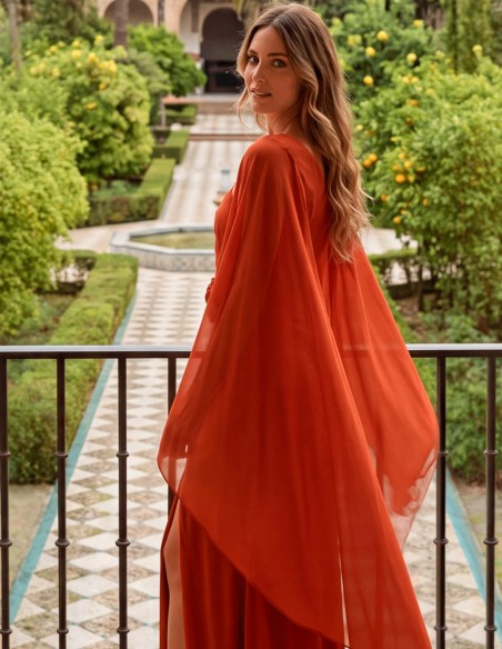 Terracotta-colored long dress with a chiffon cape and flower for a wedding guest