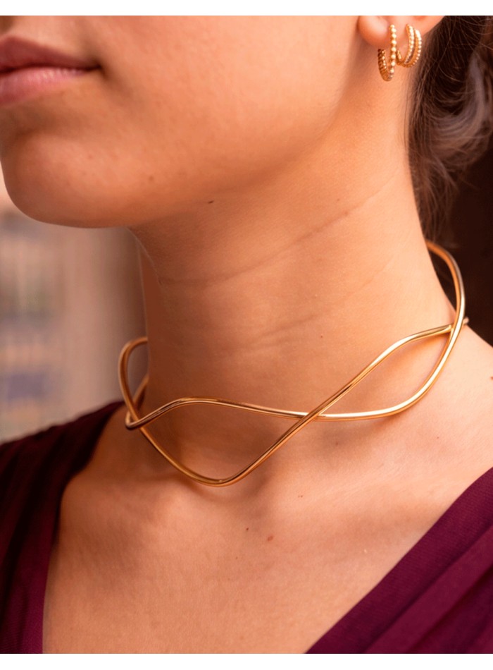Un choker dorado de líneas escultóricas que transforma cualquier estilismo