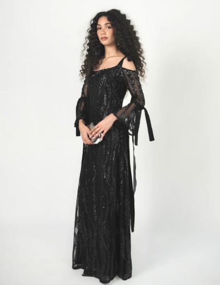 Vestido negro de tul bordado con lentejuelas, escote palabra de honor y mangas acampanadas.