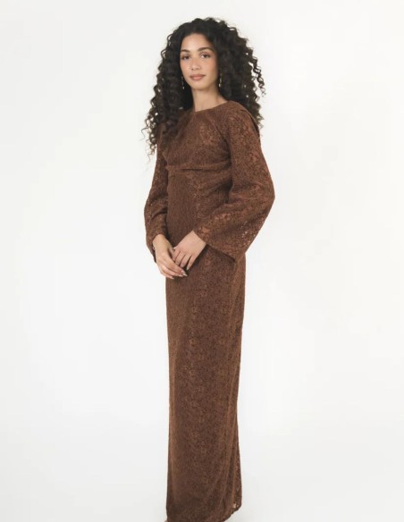 Este vestido largo en tono marrón caramelo combina la textura del encaje de terciopelo con una silueta fluida