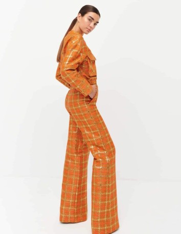 Orange flare trousers made of lamé fabric and pockets