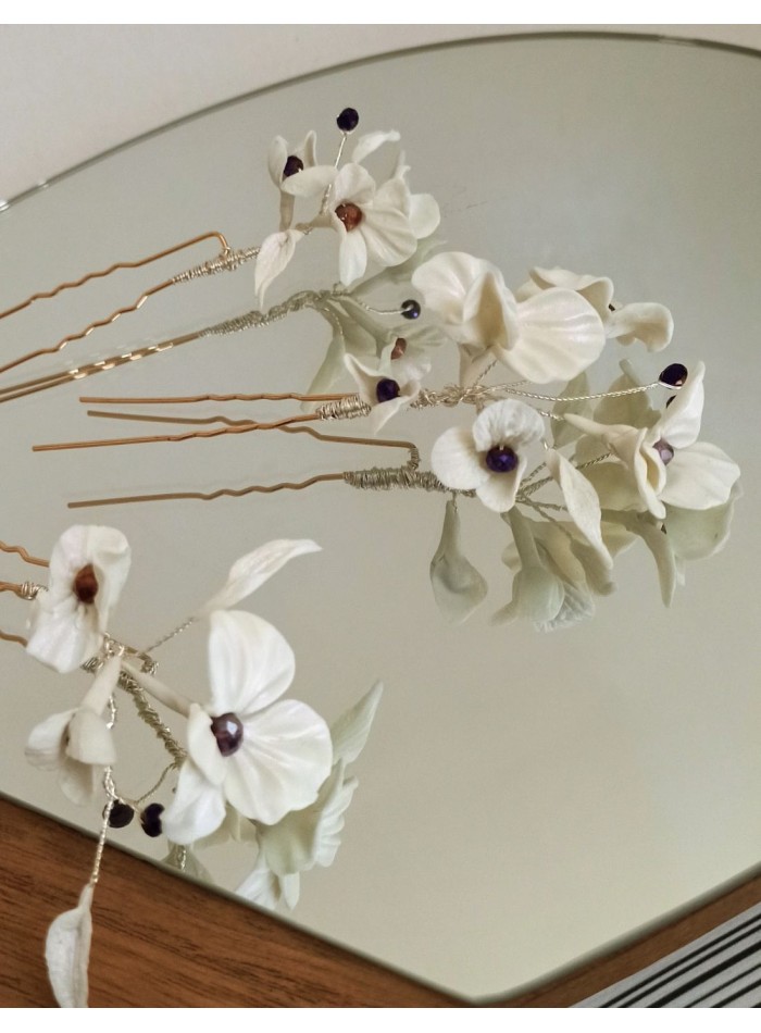 White bridal hairpins with flowers and rhinestone details.