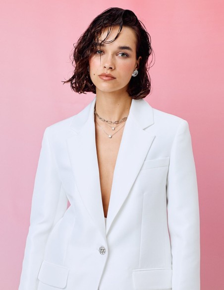 Veste blanche de style blazer avec revers et boutons ornés de pierres précieuses